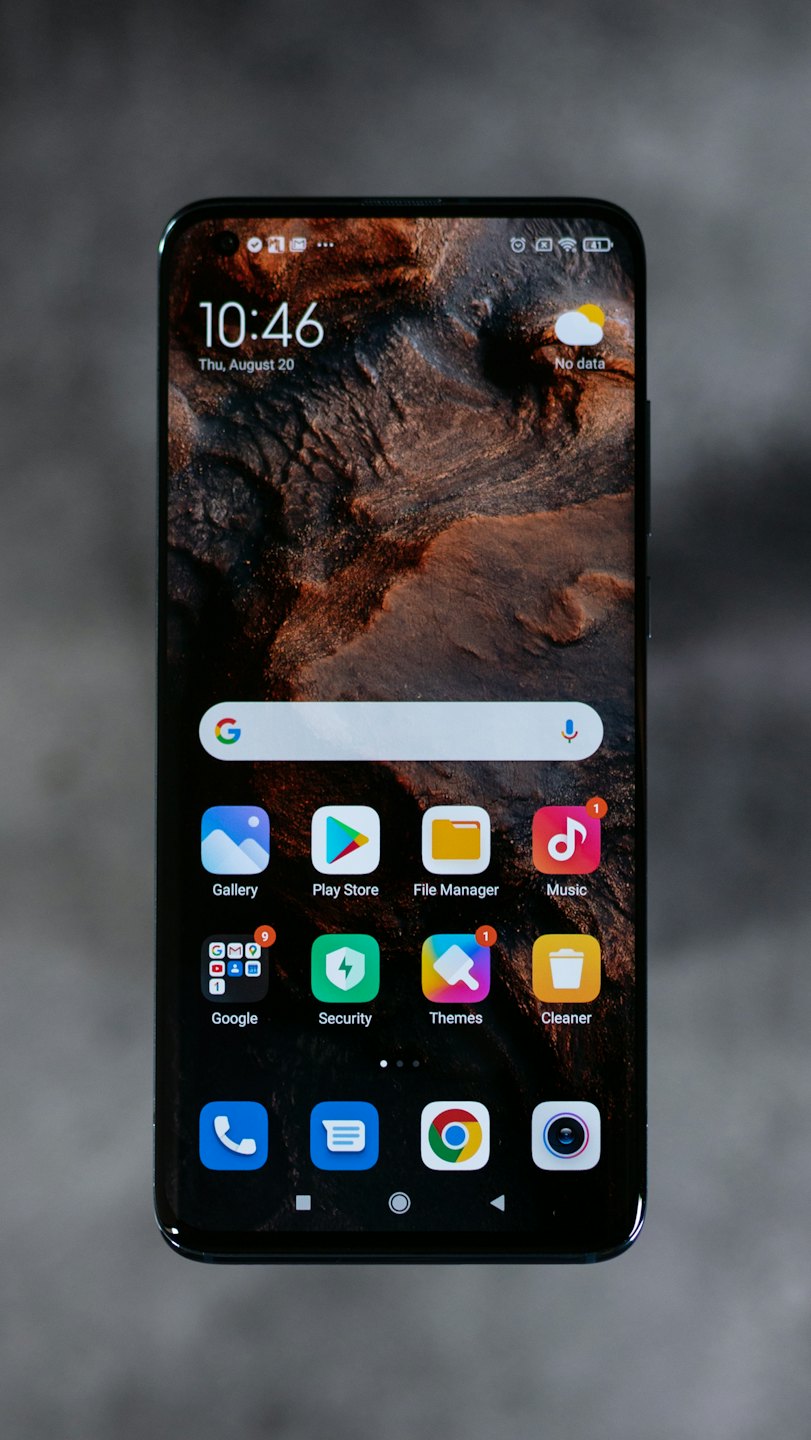 Smartphone displaying app icons and a clock against a grey background.